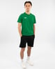 Ein Mann in einem grünen T-Shirt und schwarzen Shorts steht vor einem weißen Hintergrund.
