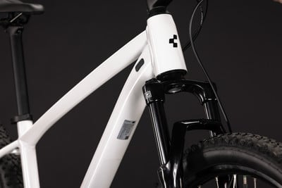 Ein weißes Mountainbike mit schwarzer Federgabel und schwarzem Sattel.