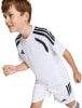 Junge in weißem Adidas Fußballtrikot und Shorts mit schwarzen Streifen.