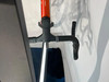 Detail eines Lenkers eines orangefarbenen Rennrads mit schwarzem Lenkerband.