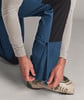 Ein Mann schließt den Reißverschluss an blauer Skihose mit beigem Stiefel.