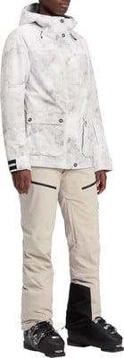 Damen-Skijacke mit Print und beige Skihose mit Skischuhen. Damen-Skijacke mit Print und beige Skihose mit Skischuhen.