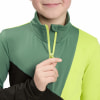 Ein Kind schließt eine grüne Jacke mit einem gelben Reißverschluss.
