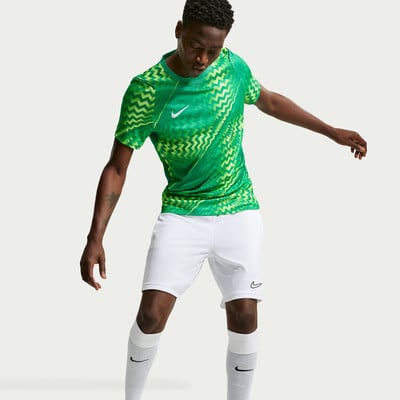 Ein Fußballspieler in einem grünen Trikot mit neonfarbenen Mustern und weißen Shorts. Ein Fußballspieler in einem grünen Trikot mit neonfarbenen Mustern und weißen Shorts.