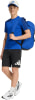 Ein Junge in einem blauen T-Shirt, schwarzen Shorts und weißen Turnschuhen mit Rucksack.