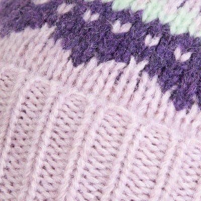 Detail einer Strickerei mit violetten und hellrosa Streifen und Muster. Detail einer Strickerei mit violetten und hellrosa Streifen und Muster.