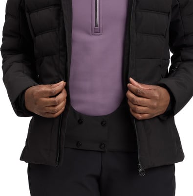 Detail einer Jacke mit lila Pullover und schwarzer Hose, Hände schließen den Reißverschluss.