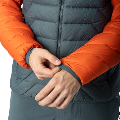 Ein Mann passt den Ärmel einer Daunenjacke mit orangefarbenen Ärmeln an. Ein Mann passt den Ärmel einer Daunenjacke mit orangefarbenen Ärmeln an.