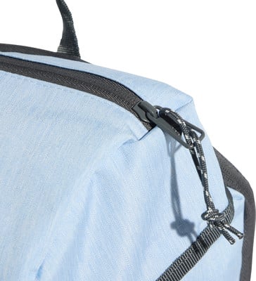 Detail eines Rucksacks mit Reißverschluss und Kordel auf hellblauem Stoff.