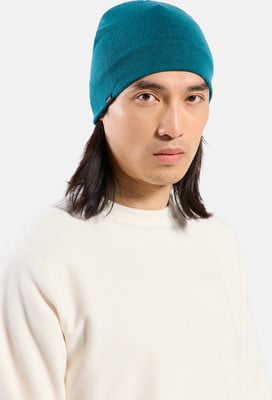 Ein Mann mit langen Haaren trägt eine dunkelgrüne Mütze und einen weißen Pullover. Ein Mann mit langen Haaren trägt eine dunkelgrüne Mütze und einen weißen Pullover.