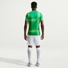 Ein Mann im grünen Fußballtrikot und weißer Hose steht von hinten.