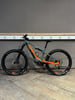 Graues KTM E-Bike mit orangefarbenen Details auf Holzboden.