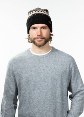 Mann mit gestrickter Mütze im norwegischen Muster und grauem Pullover.