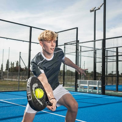 Ein junger Mann spielt Padel auf einem blauen Platz mit einem Schläger in der Hand. Ein junger Mann spielt Padel auf einem blauen Platz mit einem Schläger in der Hand.