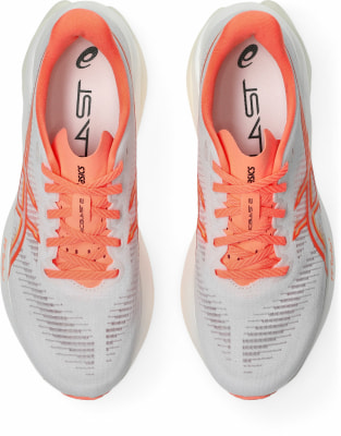 Oberansicht von weißen Laufschuhen mit orangefarbenen Details und Schnürsenkeln. Oberansicht von weißen Laufschuhen mit orangefarbenen Details und Schnürsenkeln.