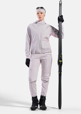 Eine Frau mit Skiern, gekleidet in einem rosa Skianzug und schwarzen Handschuhen.