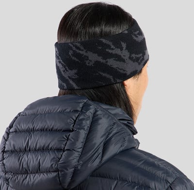 Damen-Stirnband in Schwarz mit Tarnmuster über einer dunkelblauen Jacke.