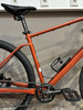 Orange Mountainbike mit schwarzem Sattel und schwarzen Pedalen.
