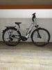 Ein silbernes E-Bike steht auf einem Holzboden in einem Raum.
