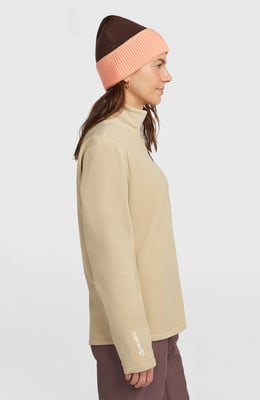 Ein Mädchen in einem beigen Fleece-Pullover und einer zweifarbigen Mütze mit Polartec-Logo. Ein Mädchen in einem beigen Fleece-Pullover und einer zweifarbigen Mütze mit Polartec-Logo.