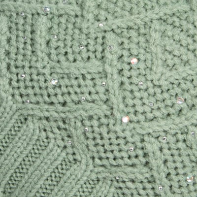 Grüner Strick mit Zopfmuster und glitzernden Steinen. Grüner Strick mit Zopfmuster und glitzernden Steinen.