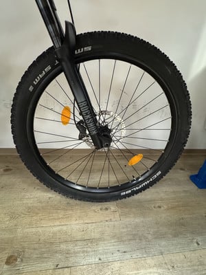 Vorderes Mountainbike-Rad mit RockShox-Federung auf Holzboden. Vorderes Mountainbike-Rad mit RockShox-Federung auf Holzboden.