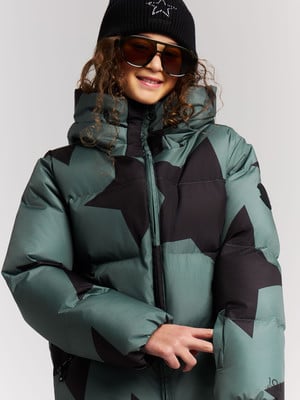 Mädchen in grüner Daunenjacke mit schwarzen Sternen und schwarzer Mütze. Mädchen in grüner Daunenjacke mit schwarzen Sternen und schwarzer Mütze.
