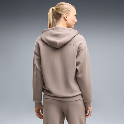 Frau in brauner Kapuzenjacke und Jogginghose, Rückansicht. Frau in brauner Kapuzenjacke und Jogginghose, Rückansicht.