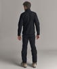 Ein Mann in schwarzer Daunenjacke und Skihose steht von hinten.