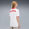 Mädchen in einem weißen Red Bulls Trikot mit roten Details vor grauem Hintergrund.