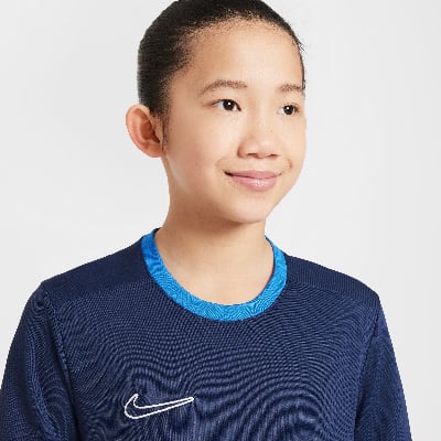 Mädchen in einem dunkelblauen T-Shirt mit Nike-Logo und blauem Kragen. Mädchen in einem dunkelblauen T-Shirt mit Nike-Logo und blauem Kragen.