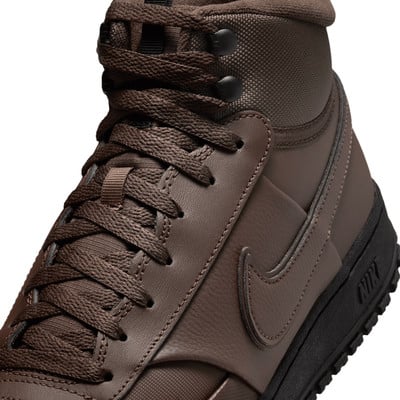 Detail eines braunen Nike-Schuhs mit Schnürsenkeln und Swoosh-Logo. Detail eines braunen Nike-Schuhs mit Schnürsenkeln und Swoosh-Logo.