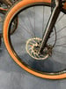 Detail eines Fahrradrades mit braunem Reifen und Scheibenbremse.