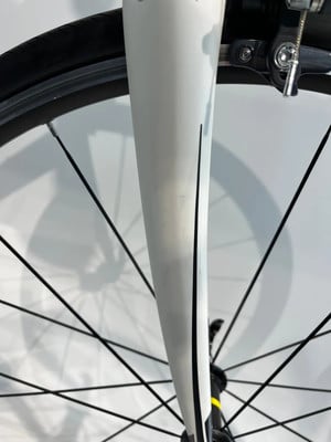 Detail einer weißen Fahrradgabel mit schwarzen Speichen. Detail einer weißen Fahrradgabel mit schwarzen Speichen.