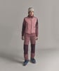 Frau in rosa Skijacke und Hose mit Mütze auf dem Kopf.