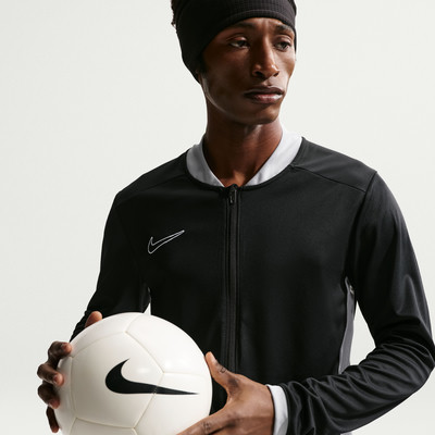 Ein Mann hält einen Fußball und trägt eine schwarze Nike-Jacke. Ein Mann hält einen Fußball und trägt eine schwarze Nike-Jacke.