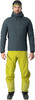 Mann in dunkelblauer Jacke, gelber Hose und Skischuhen.