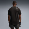 Mann von hinten in einem schwarzen Kurzarmshirt und dunklen Shorts.