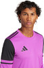 Ein Mann in einem pinken T-Shirt mit schwarzen Ärmelstreifen und Adidas-Logo.