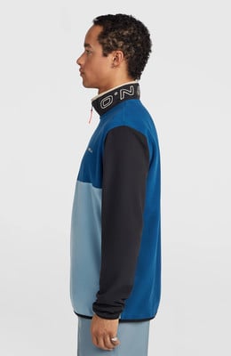Ein Mann in einem blauen Fleece-Pullover mit O'Neill-Logo am Kragen. Ein Mann in einem blauen Fleece-Pullover mit O'Neill-Logo am Kragen.