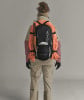Rückansicht eines Bergsteigers mit Rucksack, Helm und Seil auf dem Rücken.