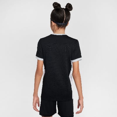 Rückansicht eines Mädchens in einem schwarzen T-Shirt mit weißen Streifen und schwarzen Shorts.