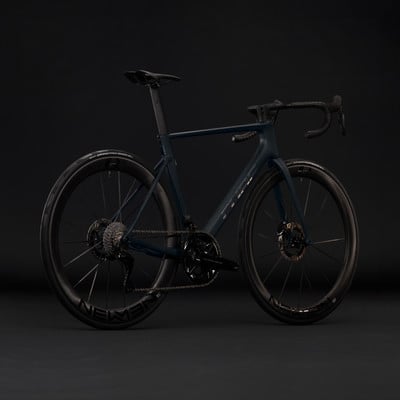 Dunkelblaues Rennrad mit Carbonfelgen vor schwarzem Hintergrund.