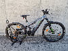 Ein Genesis E-Mountainbike mit Federung steht auf einem Pflaster.