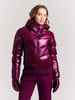 Junge Frau in glänzender lila Daunenjacke und Handschuhen.