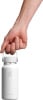 Eine Hand hält eine weiße Hydro Flask Flasche am Henkel.