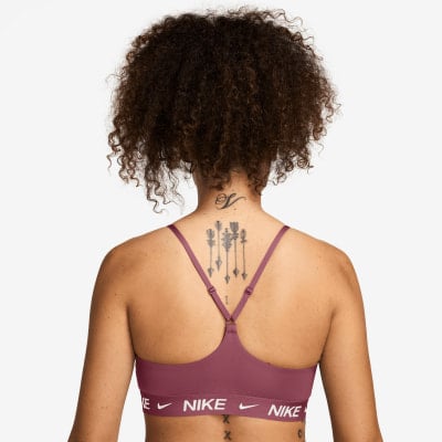 Rückansicht einer Frau mit Tattoo auf dem Rücken in einem rosafarbenen Nike BH.