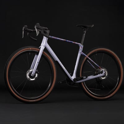 Modernes Gravelbike in Lavendelfarbe mit buntem Muster auf dem Rahmen.