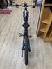 Ein blaues E-Mountainbike mit schwarzem Sattel steht auf Holzboden.