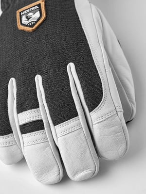Detail eines Hestra-Handschuhs mit Logo und Lederdetails auf weißem Hintergrund.